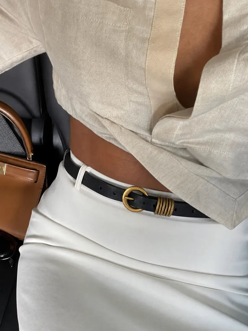 White tank and blue jeans with a gold oval-buckle belt