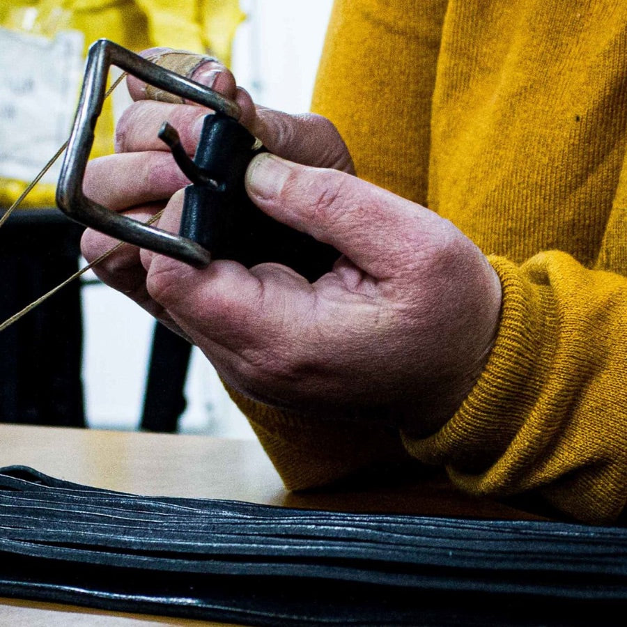 A craftsman fitting a buckle to a leather belt in the workshop