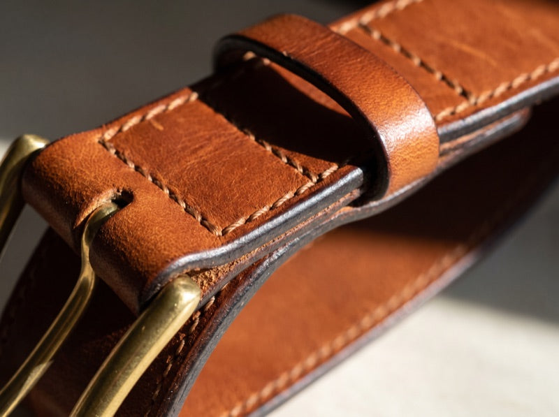 The buckle fold of a leather belt showing the stitch line and burnished edge