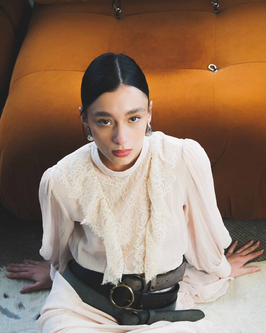 A wide leather belt worn over a cream dress