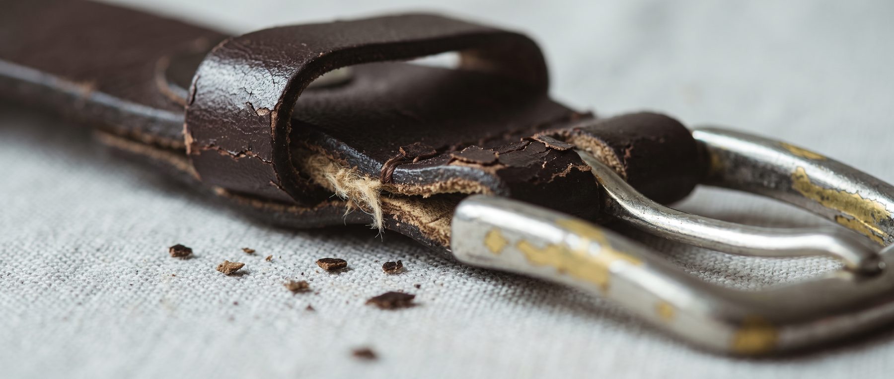 A worn leather belt showing visible wear at the buckle fold